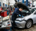Mechanic fixing headlight on a silver car with open hood in auto repair shop